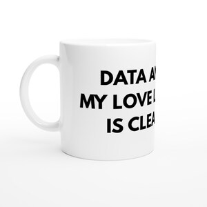 Può includere: Una tazza in ceramica bianca con un manico sul lato sinistro. La tazza presenta un testo nero stampato sul lato che recita: DATA AND MY LOVE IS CLEAR.