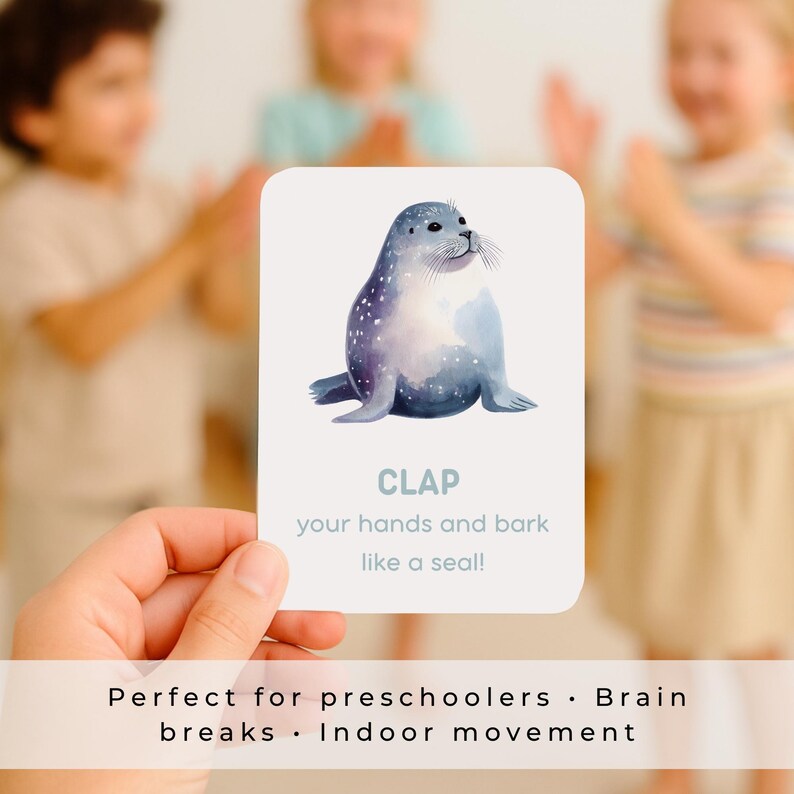 Puede incluir: Una tarjeta blanca con una ilustraci&oacute;n de acuarela de una foca. La tarjeta dice "CLAP your hands and bark like a seal!" y est&aacute; dise&ntilde;ada para preescolares. La tarjeta se sostiene frente a ni&ntilde;os aplaudiendo.