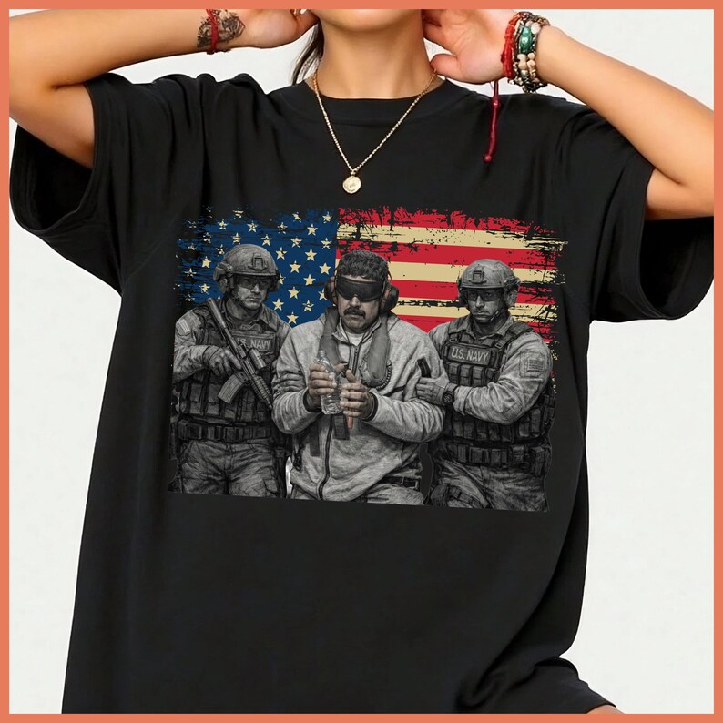 May include: Black t-shirt featuring a graphic of three soldiers in front of a distressed American flag. The soldiers are wearing military gear. The image has a vintage, worn look.