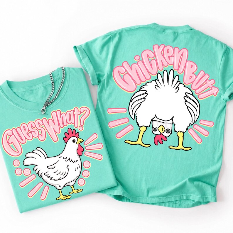 Puede incluir: Dos camisetas turquesas con dise&ntilde;os de pollos. Una camiseta dice "Guess What?" con un pollo de dibujos animados. La otra dice "Chicken Butt" con el trasero de un pollo. Ambos dise&ntilde;os tienen detalles en rosa sobre un fondo turquesa.
