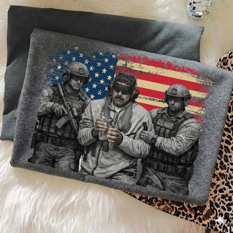 May include: Gray t-shirt featuring a graphic of three U.S. Navy soldiers with an American flag backdrop. The design includes detailed illustrations of the soldiers in uniform, holding weapons and equipment. The flag design has a distressed look.