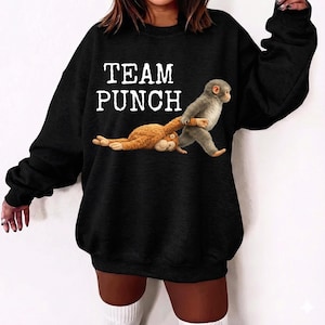 May include: Black sweatshirt with the text "TEAM PUNCH" in white. The graphic shows two monkeys, one pulling the other. The sweatshirt is a casual style, suitable for everyday wear.
