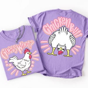 May include: Two lavender t-shirts with chicken-themed graphics. One shirt features a white chicken with the text "Guess What?" in pink. The other shirt has a chicken's rear with the text "Chicken Butt" in pink.