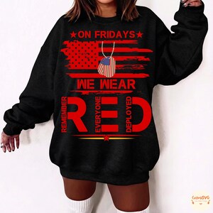 May include: Black sweatshirt featuring the text "ON FRIDAYS WE WEAR RED" in red, with an American flag design and dog tag graphic. The sweatshirt also includes the words "REMEMBER EVERYONE DEPLOYED".