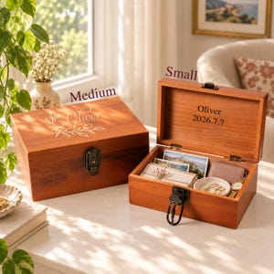 May include: Two rectangular wooden keepsake boxes with metal latches. The closed medium box features a floral engraving and the name Oliver. The open small box is engraved with Oliver and 2026.7.7, containing photos, a dish, and a watch.