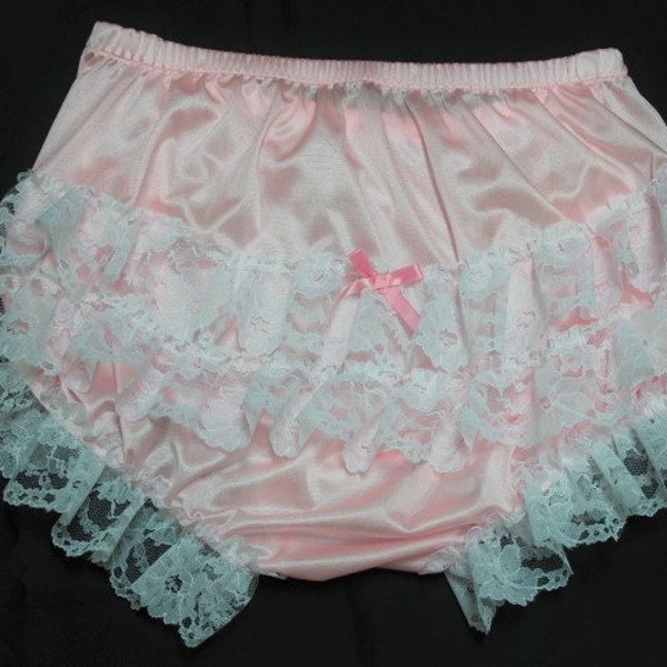 May include: Pink satin underwear with white lace trim and a small pink bow. The underwear has a ruffled design with multiple layers of lace. The elastic waistband is visible at the top.