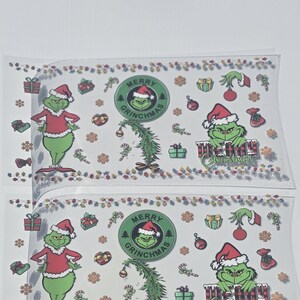 May include: Clear plastic Christmas-themed stickers featuring the Grinch in a Santa hat. The stickers include the text "Merry Grinchmas" and various holiday-themed graphics like presents, ornaments, and candy canes.