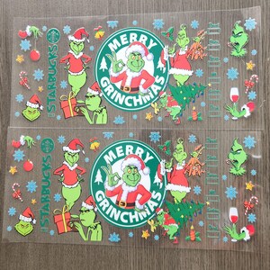 May include: Two clear plastic sheets with a Christmas-themed design featuring the Grinch. The design includes the Starbucks logo, the words "Merry Grinchmas," and various Grinch illustrations in a Santa suit. Decorative elements include snowflakes, ornaments, and candy canes.