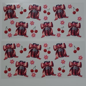 May include: A sheet of stickers featuring Dr Pepper soda cans with red bows and cherries. The stickers are on a white background.