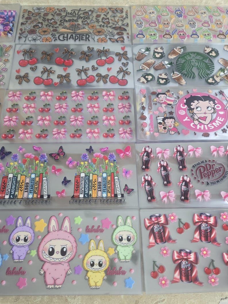 May include: A collection of clear sticker sheets featuring various designs. These include cherries, bows, butterflies, cartoon characters, and text such as "CHAPTER" and "labubu". Some stickers have a floral theme, and others feature Dr. Pepper cans.