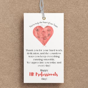 May include: A white gift tag with a gray string, featuring a red heart illustration with a stick figure and the text "You're truly the heart of our Team." The tag also includes text thanking HR professionals.