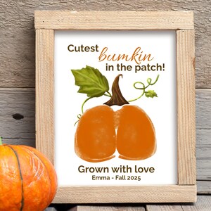 Pode incluir: Uma impressão emoldurada com uma ilustração em aquarela de uma abóbora. A abóbora é laranja com um caule marrom e folhas verdes. O texto diz "Cutest bumkin in the patch!" e "Grown with love Emma - Fall 2025".