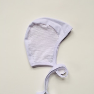 May include: White baby bonnet with a mesh panel and tie strings.