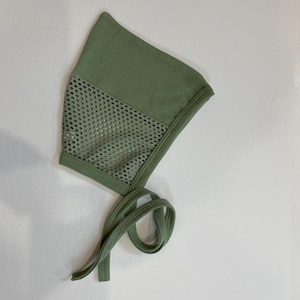 May include: A sage green baby bonnet with a mesh panel and tie strings.