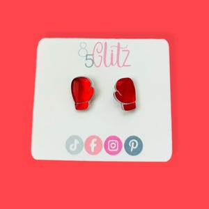May include: A pair of red boxing glove stud earrings on a white card with the text "85Clitz" and social media icons.