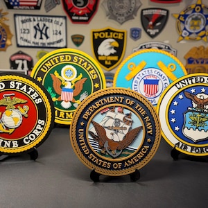 May include: A collection of five circular plaques representing United States military branches, including the Marine Corps, Army, Coast Guard, Navy, and Air Force. Each plaque features the official emblem, colors, and text of its respective branch.