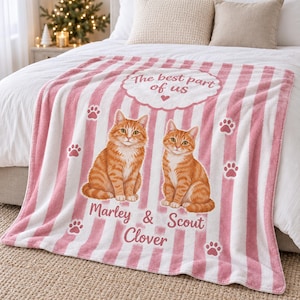 May include: A soft throw blanket featuring vertical pink and white stripes, two orange tabby cats, and paw print accents. The text reads The best part of us, Marley & Scout, and Clover in a decorative cloud-shaped frame and script font.