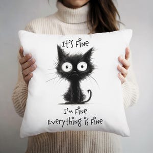May include: White pillow with a black and white illustration of a cat with the text "It's Fine, I'm Fine, Everything is Fine."
