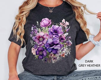 May include: Dark grey heather t-shirt featuring a watercolor floral design in shades of purple, pink, and white. The text "DARK GREY HEATHER" is printed in white on the lower right side of the shirt.