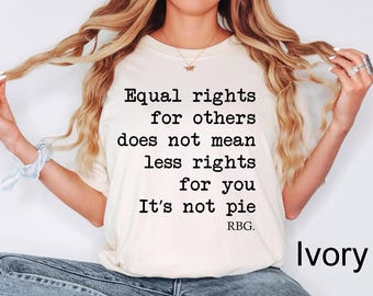 May include: Ivory-colored t-shirt with the text "Equal rights for others does not mean less rights for you. It's not pie. RBG." The shirt is a crew neck and is being worn.