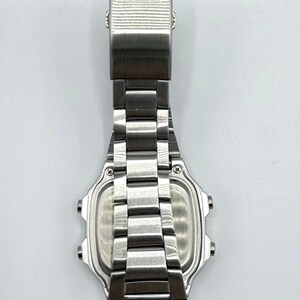 May include: A stainless steel Casio digital watch, viewed from the back. The watch features a rectangular face with a silver-tone metal band and clasp. The word "CASIO" is embossed on the clasp.
