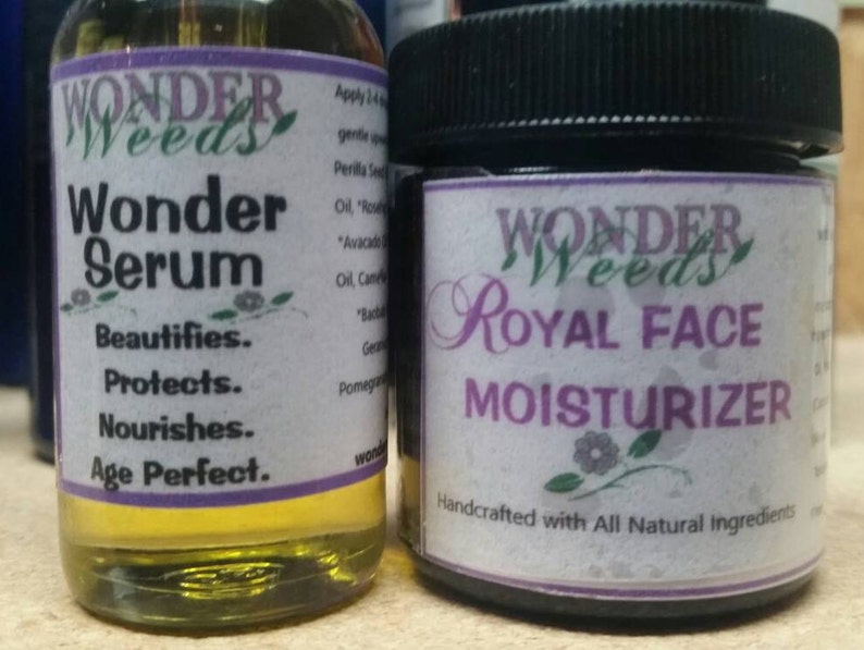 Puede incluir: Dos botellas de vidrio con etiquetas moradas. La botella de la izquierda est&aacute; etiquetada "Wonder Weeds Wonder Serum Beautifies. Protects. Nourishes. Age Perfect." La botella de la derecha est&aacute; etiquetada "Wonder Weeds Royal Face Moisturizer Handcrafted with All Natural Ingredients".