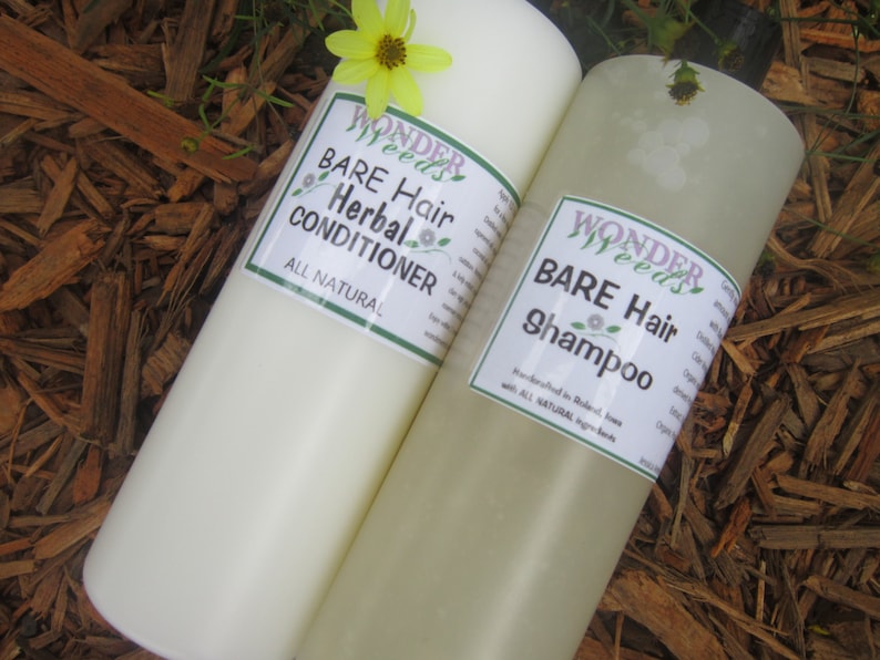 May include: Two cylindrical bottles of hair care products, one labeled "Bare Hair Herbal Conditioner" and the other "Bare Hair Shampoo." Both have white labels with green borders and the "Wonder Weeds" logo. A yellow flower sits atop the bottles, with a wood chip background.