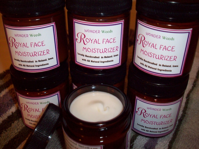 May include: Multiple brown glass jars with black lids containing a white cream. Each jar has a label that reads "Wonder Weeds Royal Face Moisturizer Locally Handcrafted in Roland, Iowa with All Natural Ingredients."