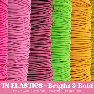 May include: Assortment of colourful elastic string spools in pink, red, green, yellow, and lime green. The spools are labelled "TN ELASTICS - Bright & Bold 2MM ELASTIC STRINGS - 2 METRES (80 INCHES)"