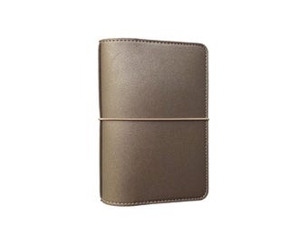 May include: A gold leather bound journal with an elastic closure.