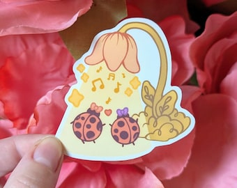 May include: A sticker featuring two cartoon ladybugs with bows, under a flower-shaped light. The ladybugs are red with black spots. The light is yellow and orange, with musical notes and stars.