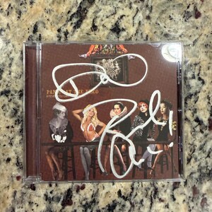 May include: A Panic! At The Disco A Fever You Can't Sweat Out CD case with a brown cover featuring five people sitting at a bar. The cover has white ink signatures across the front, obscuring parts of the image and the band name text.