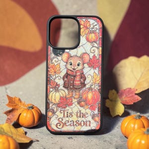 May include: A black phone case featuring a stained glass style illustration of a mouse wearing a scarf and coat, surrounded by autumn leaves, pumpkins, and acorns. The text 'Tis the Season' is printed in a decorative font at the bottom.