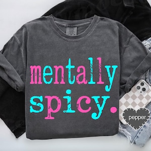 May include: Dark gray sweatshirt with the words "mentally spicy" in pink and turquoise lettering. The sweatshirt is shown with a phone case and a heart-shaped tag that says "pepper".