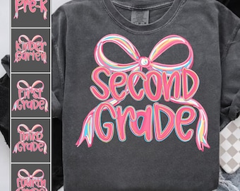 May include: Dark gray t-shirt with a large pink and rainbow bow design and the words "Second Grade" in pink script. Additional designs for Pre-K, Kindergarten, First, Third, and Fourth Grade are also shown.