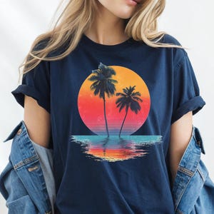 a woman wearing a t - shirt with a sunset and palm trees on it