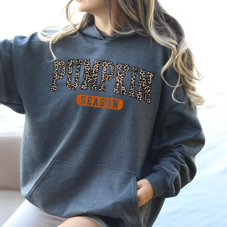 A woman wearing a grey hoodie with the word "Pumpkin" printed on it.
