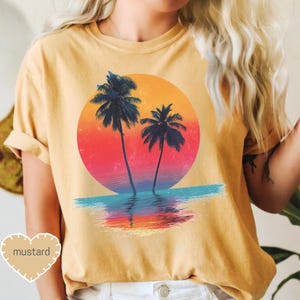a woman wearing a t - shirt with a sunset and palm trees on it