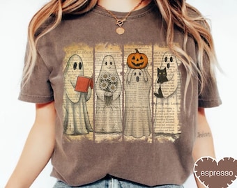 May include: A brown t-shirt featuring a Halloween-themed graphic. The graphic shows four ghosts, each with a unique element: a book, flowers, a pumpkin, and a black cat. The background is a vintage book page design.