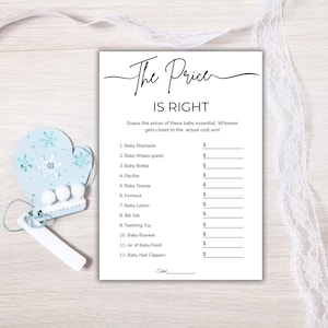 May include: A baby shower game card titled "The Price is Right" with a list of baby essentials. A light blue mitten-shaped ornament with snowflake details and a white tag are on the left.