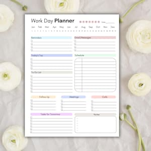 K&ouml;nnte beinhalten: Ein wei&szlig;er Work Day Planner mit Abschnitten f&uuml;r Erinnerungen, Aufgaben und Notizen. Der Planer enth&auml;lt einen Kalender und Abschnitte f&uuml;r E-Mails, Besprechungen und Anrufe. Der Planer ist mit wei&szlig;en Blumen verziert.