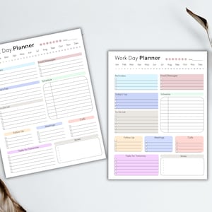 K&ouml;nnte beinhalten: Zwei undatierte "Work Day Planner"-Bl&auml;tter mit pastellfarbenen Abschnitten f&uuml;r Erinnerungen, Aufgaben und Notizen. Die Bl&auml;tter haben Abschnitte f&uuml;r die Tage des Monats und die Monate des Jahres. Ein getrockneter Pflanzenstiel befindet sich im Hintergrund.