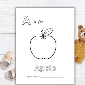May include: Black and white illustrated page with the letter "A" and the word "Apple". The image of an apple is in the center. The text "A is for" is above the apple, and the word "Apple" is below. A teddy bear and baby shoes are in the background.