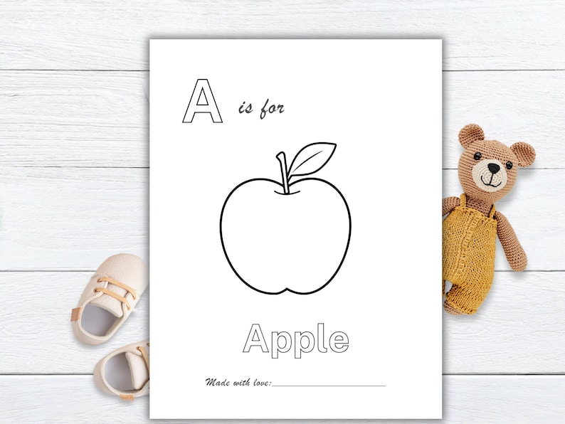 May include: Black and white illustrated page with the letter "A" and the word "Apple". The image of an apple is in the center. The text "A is for" is above the apple, and the word "Apple" is below. A teddy bear and baby shoes are in the background.