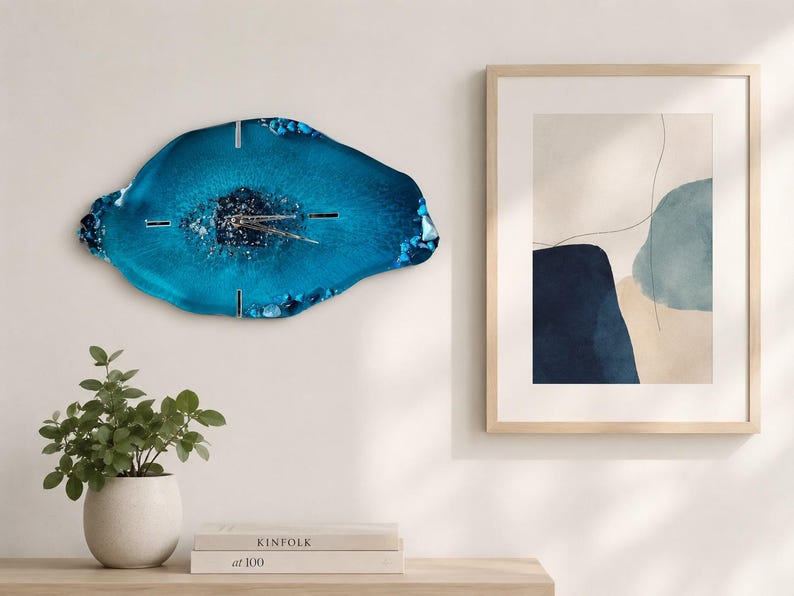 May include: An irregular, geode-inspired wall clock featuring a deep blue resin surface with a textured, crystalline center. The clock has silver-toned hands and thin, metallic hour markers positioned at the twelve, three, six, and nine o'clock positions.