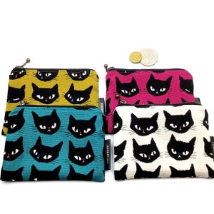 May include: Four small zippered pouches with black cat faces printed on them. The pouches are in four different colours: yellow, pink, teal, and white.