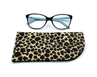 May include: A brown tortoise shell eyeglasses case with a leopard print design. The case is closed and the eyeglasses are sitting on top of the case.