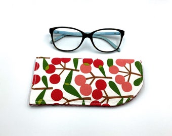 May include: A white and red patterned glasses case with a black framed glasses on a white background.