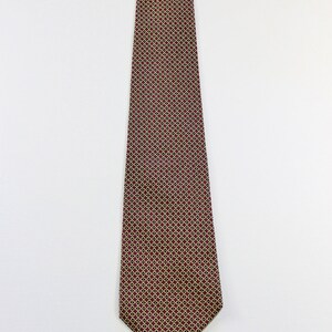 May include: A burgundy necktie with a geometric pattern of small gold circles.