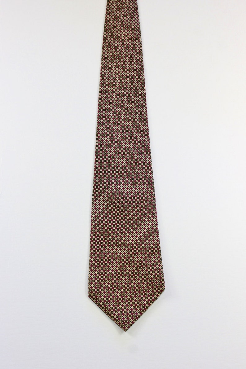 May include: A burgundy necktie with a geometric pattern of small gold circles.